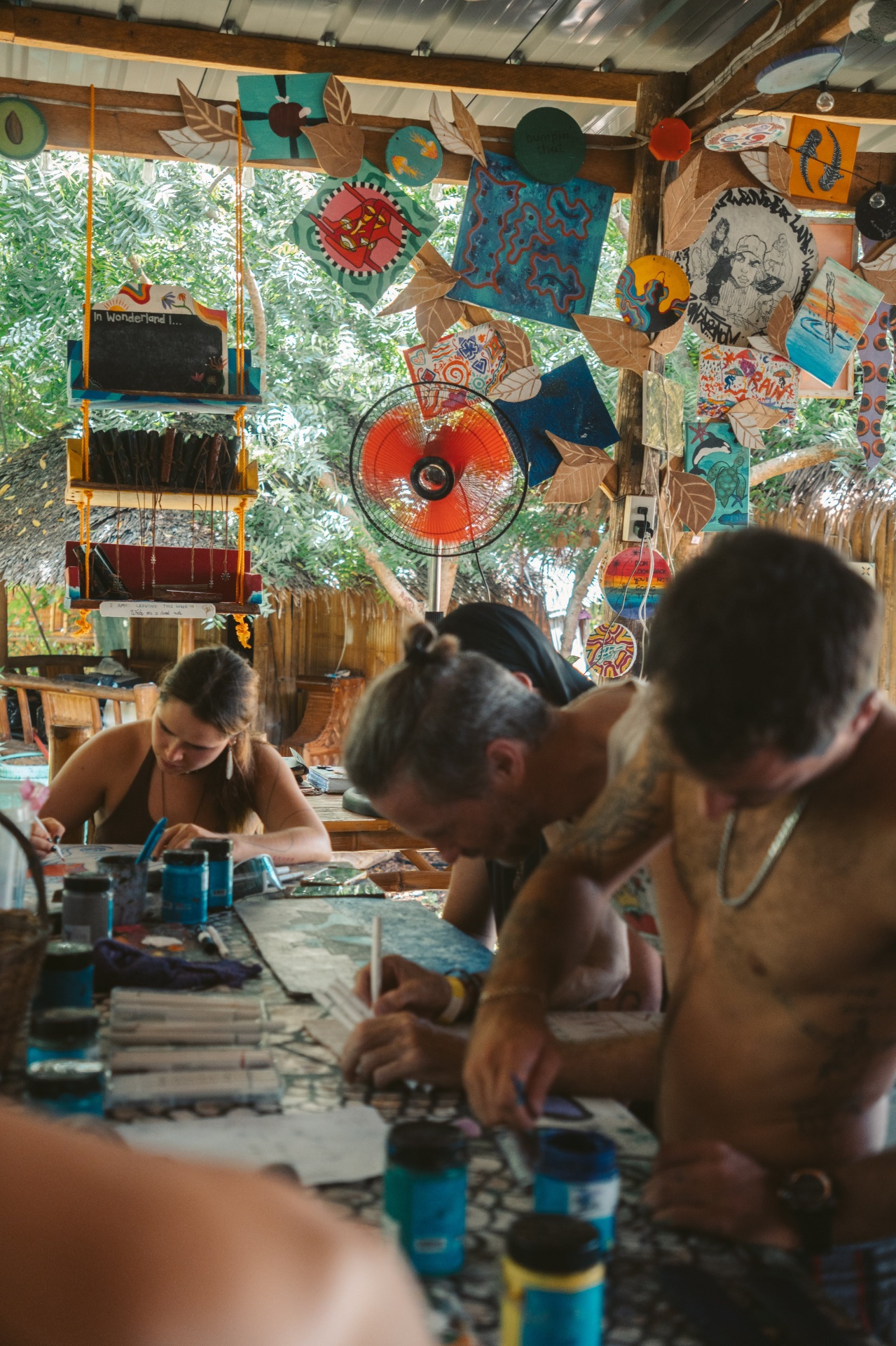 People drawing and making art together under hanging artwork at Wonderland.