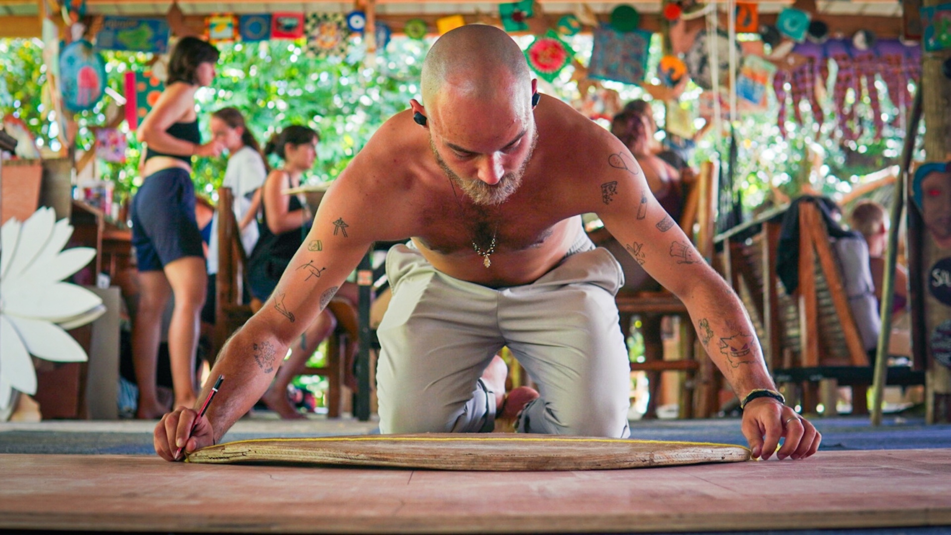 A maker measuring and sketching on a surfboard in the Wonderland workshop.